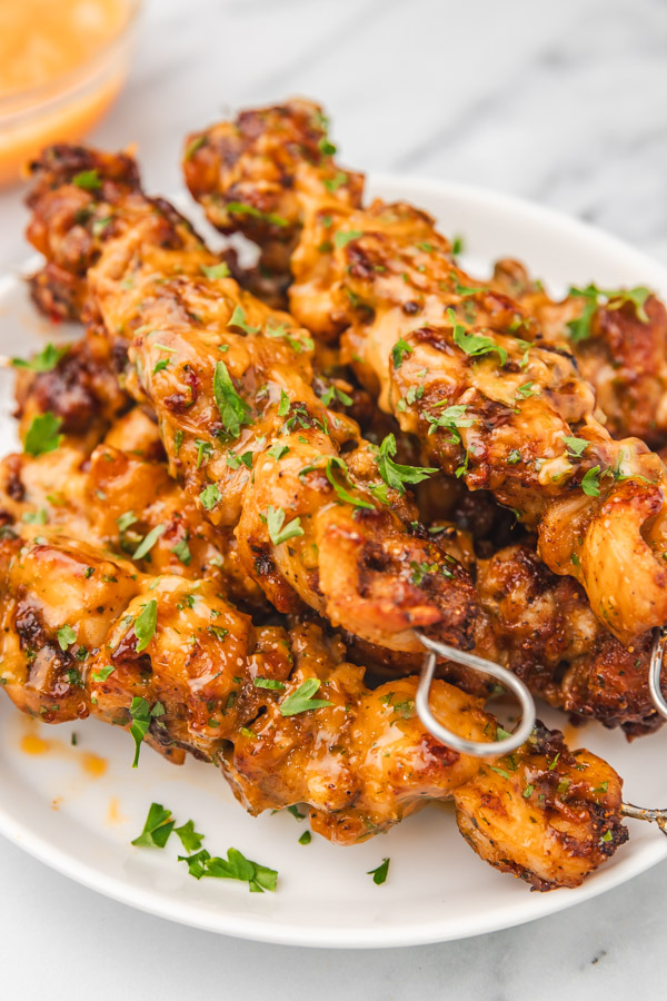 chicken skewers on a plate garnished with fresh parsley.